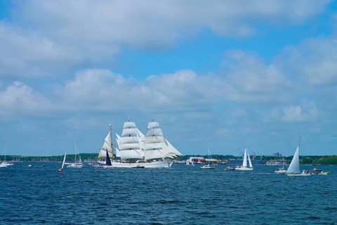 A magnificent tall ship Gorch Fock with white sails in a field of boats, Windjammer Parade Kiel