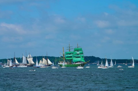 Many sailing boats on the ocean, a large green sailing ship Alexander von Humbold 2 in the centre