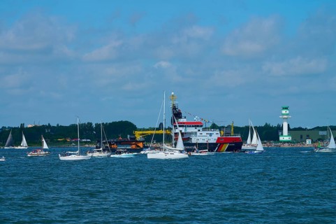 Large ship Arkona Coast Guard and numerous smaller sailing boats in the water in front of a