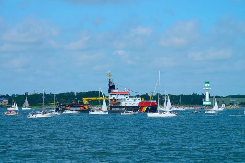 Various boats and a large ship Arkona Coast Guard on the sea next to a lighthouse Friedrichsort,