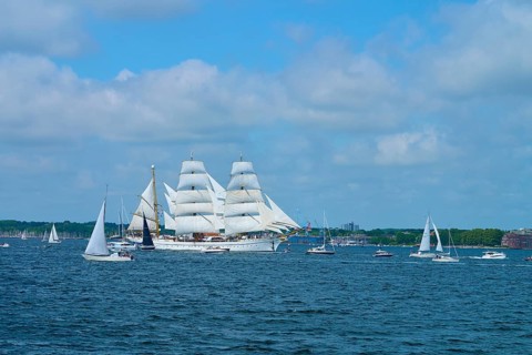 A large sailing ship Gorch Fock surrounded by smaller boats on the water, Windjammer Parade Kiel