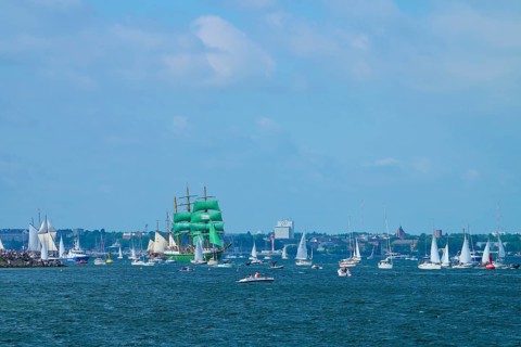 Green tall ship Alexander von Humbold 2 among many boats near a town, Windjammer Parade Kiel 2025,
