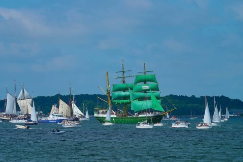 Large sailing regatta on the sea. Various ships, including a striking green sailing ship Alexander