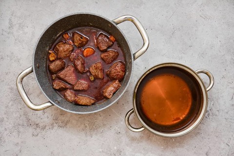 Chunks of tender beef and vegetables are slow-cooked in a pot, creating a hearty stew with dark