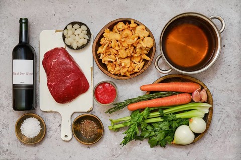 Fresh vegetables and tender beef are arranged on a kitchen counter, preparing for a delicious stew.