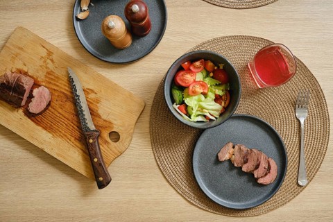 Slices of succulent duck breast are laid out on a cutting board beside a vibrant salad filled with