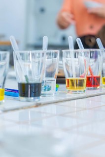 Several glasses on a table filled with colourful liquids and pipettes ready for an experiment,