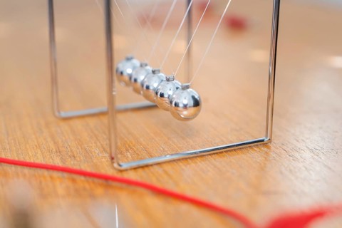 Swinging Newton pendulum on a wooden table shows movement and physical laws, Youth Research Centre