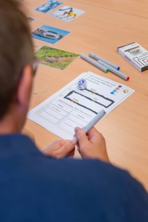 Man plans or documents on paper with markers and small robot on a table, Youth Research Centre