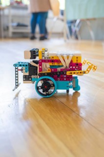 Colourful Lego robot with wheels on a wooden floor demonstrates technical creativity, Youth