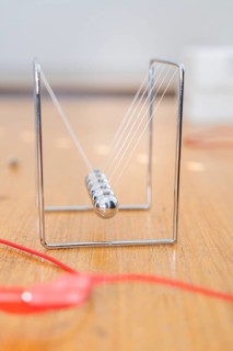 Metallic Newton pendulum with resting spheres on a wooden table, Youth Research Centre