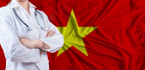 Doctor with crossed arms on Vietnam flag. Vietnam health and care concept. Female doctor on Vietnam