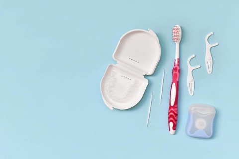 Top view of dental clear aligners, toothbrush, toothpicks and floss on blue background with copy