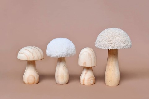 Four wooden mushroom ornaments in a row on beige background
