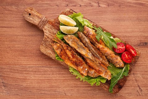 Fried crispy red mullet fish, on a wooden chopping board, with lime, no people