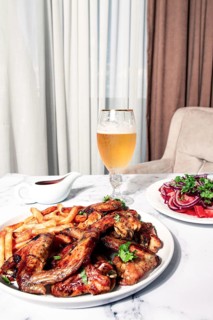 Delicious barbecue chicken wings, with French fries, salad and a refreshing drink, at a cozy table,
