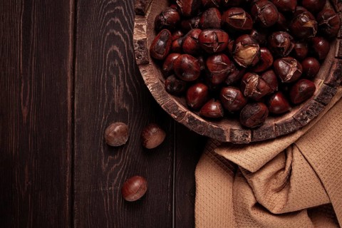 Roasted chestnuts, in a wooden plate, top view, homemade, no people