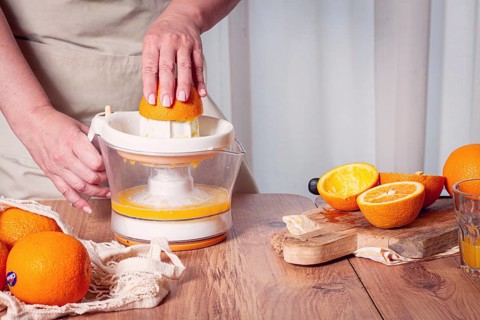 Preparation of freshly squeezed orange juice, using a juicer, in a cozy kitchen setting
