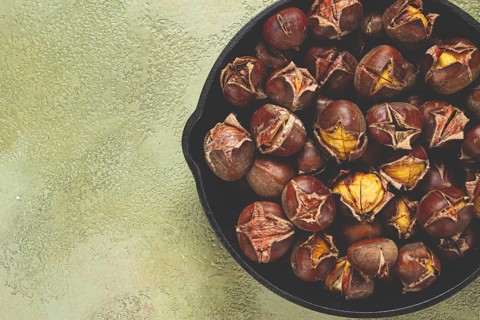 Roasted chestnuts, in an iron pan, wooden table, top view, no people, rustic style