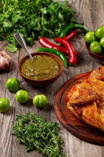Baked tobacco chicken, served with tkemali sauce, on a wooden table, Georgian cuisine, rustic