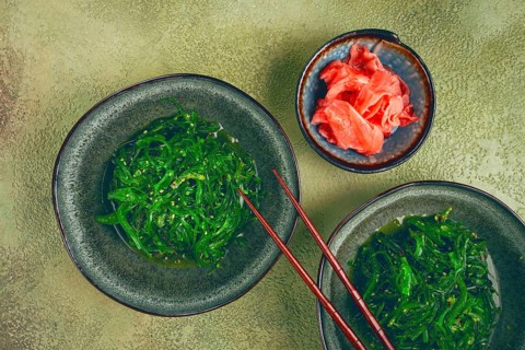 Chuka salad made from fresh seaweed, with sesame dressing, two bowls with chopsticks and pickled