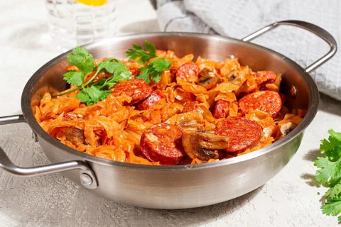 Polish dish bigos, in a stainless steel pan, stewed meat with cabbage, chorizo sausages, mushrooms,