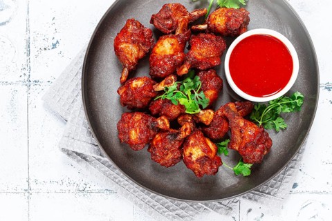 Crispy pieces of fried chicken, on a plate with sauce and herbs, in a modern kitchen environment,