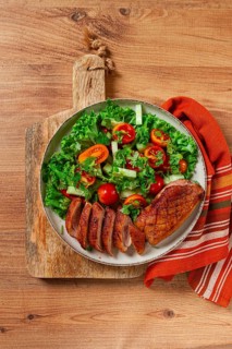 Delicious grilled duck breast served with fresh garden salad and cherry tomatoes at a rustic dining