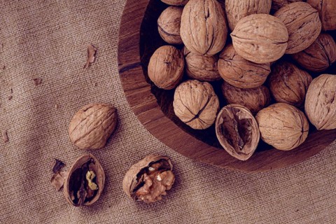 Freshly picked walnuts, in a wooden bowl, on a wooden table, rustic style, no people