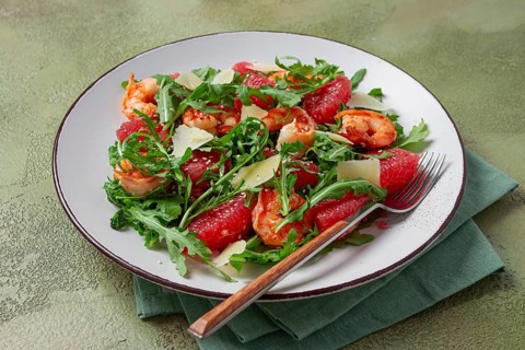 Fresh shrimp salad with arugula, grapefruit, and parmesan served in a bowl