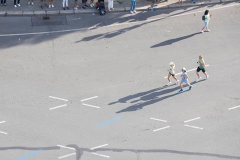 Runners with long shadows on the big star seen from the Victory Column at the 51st BMW Berlin