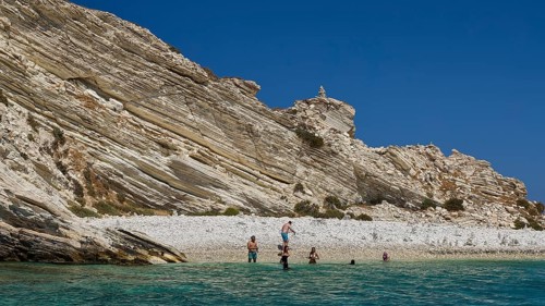 Group of people swimming in clear water in front of rocky beach landscape, White Cliffs, White