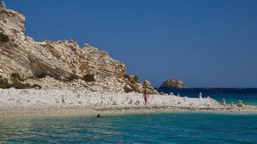 Rocks and a pebble beach meet turquoise waters under a clear sky, White Cliffs, White Beach, Makri