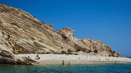 Rocky coast with people walking along the beach and swimming in the sea, White Cliffs, White Beach,