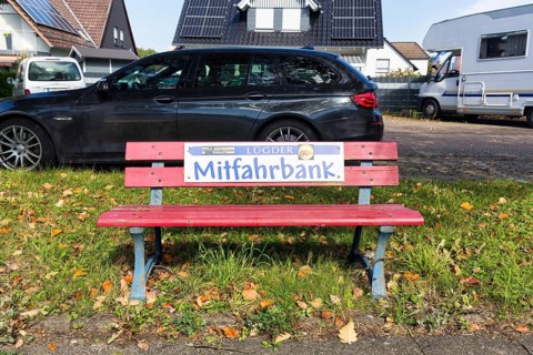 Red bench at the roadside, sign with inscription Mitfahrbank, Mitfahrerbank, symbol photo, carpool,