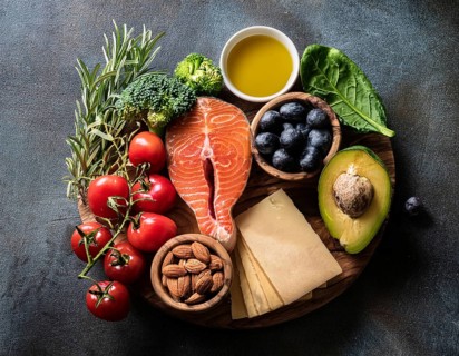 A vibrant assortment of healthy food ingredients, including fresh vegetables, salmon, nuts, and