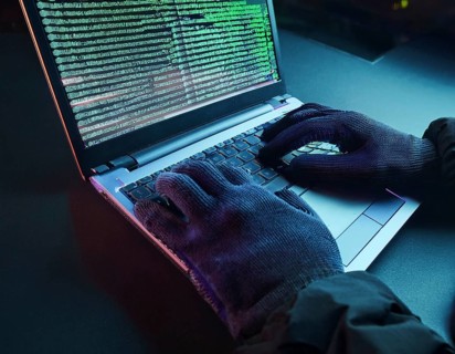 Cybersecurity threat depicted by gloved hands operating a computer, commands displayed on the