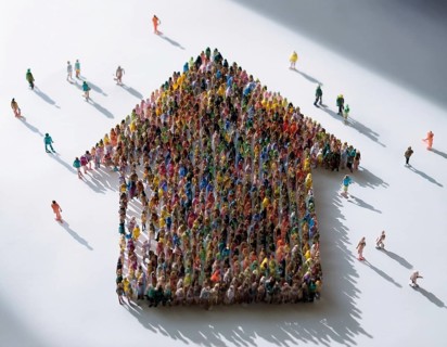 A concept photograph depicting numerous individuals arranged to form the shape of a house. Symbolic