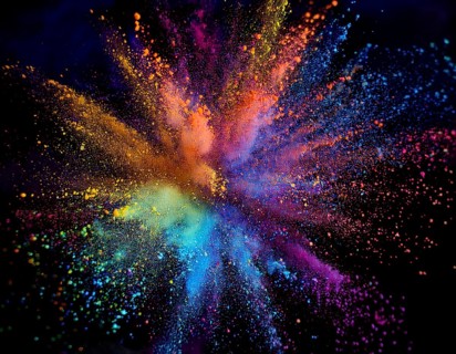 Vibrant and energetic multicolored powder explosion captured against a dark background. Evoking