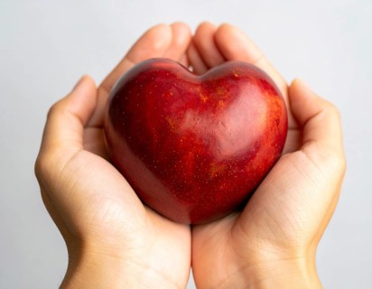 Close-up of hands holding heart-shaped fruit, symbolizing healthy lifestyle, love, nutrition,