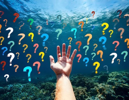 An extended hand emerges from water surrounded by floating question marks, artistically