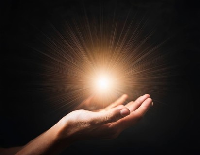 Image of open hand embracing a radiant light source, embodying concepts of hope, spirituality, and