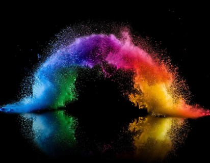 Vibrant and energetic multicolored powder explosion captured against a dark background. Evoking