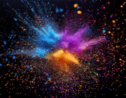 Vibrant and energetic multicolored powder explosion captured against a dark background. Evoking