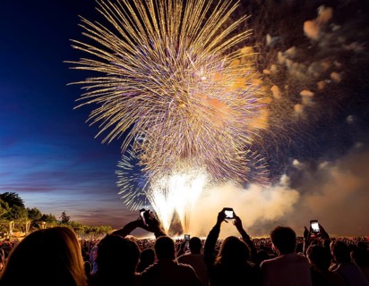 Thrilling fireworks illuminate the dark sky as a crowd gathers to enjoy the dazzling display,