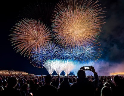 Thrilling fireworks illuminate the dark sky as a crowd gathers to enjoy the dazzling display,
