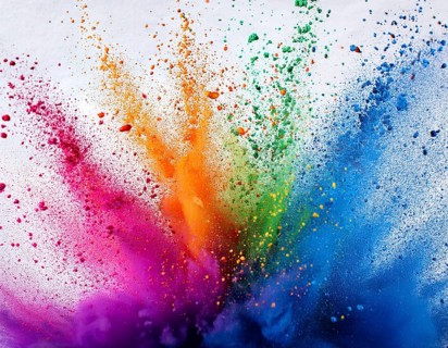 Vibrant and energetic multicolored powder explosion captured against awhite background. Evoking