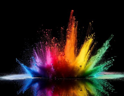 Vibrant and energetic multicolored powder explosion captured against a dark background. Evoking