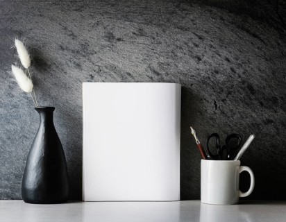 A clean and modern office workspace featuring a pen holder, notebook, and ceramic vase against a