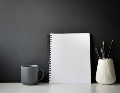 A clean, organized workspace featuring decorative objects, a white blank canvas, greenery, and